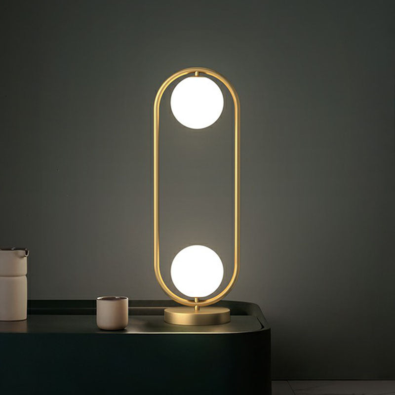 Candeeiro de mesa com 2 globos - Acabamento dourado com cúpula de vidro e armação oval